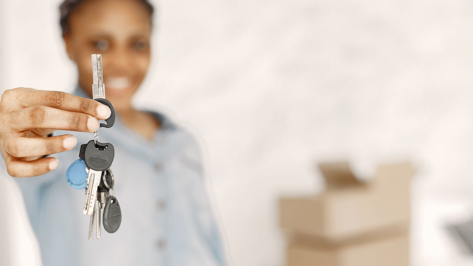 Person holding house keys with moving boxes in the background